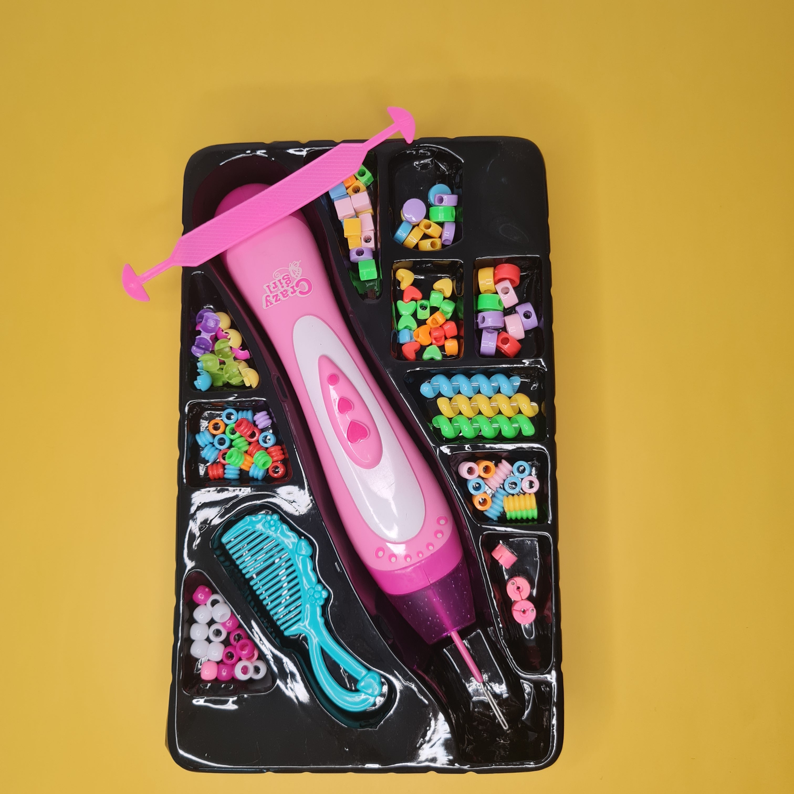 Pink crafting tool with colorful beads and accessories on a yellow background